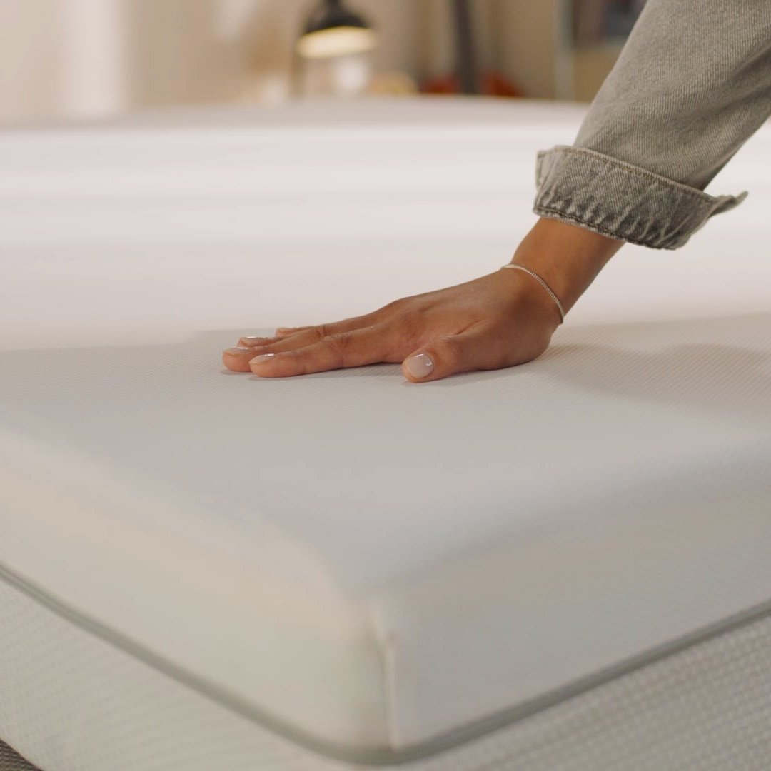 Person pressing the mattress surface to show its feel.
