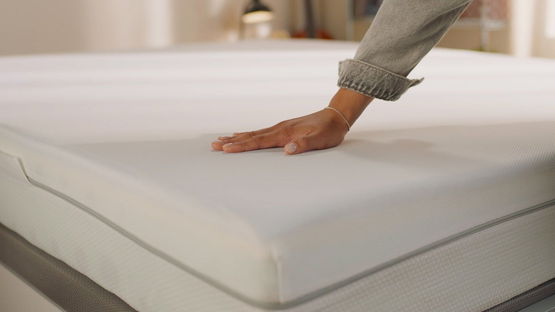 Person pressing the mattress surface to show its feel.