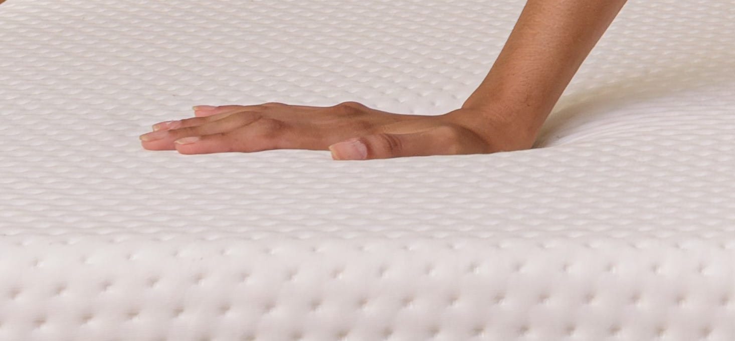 Moça aplicando pressão sobre um colchão firme Emma
