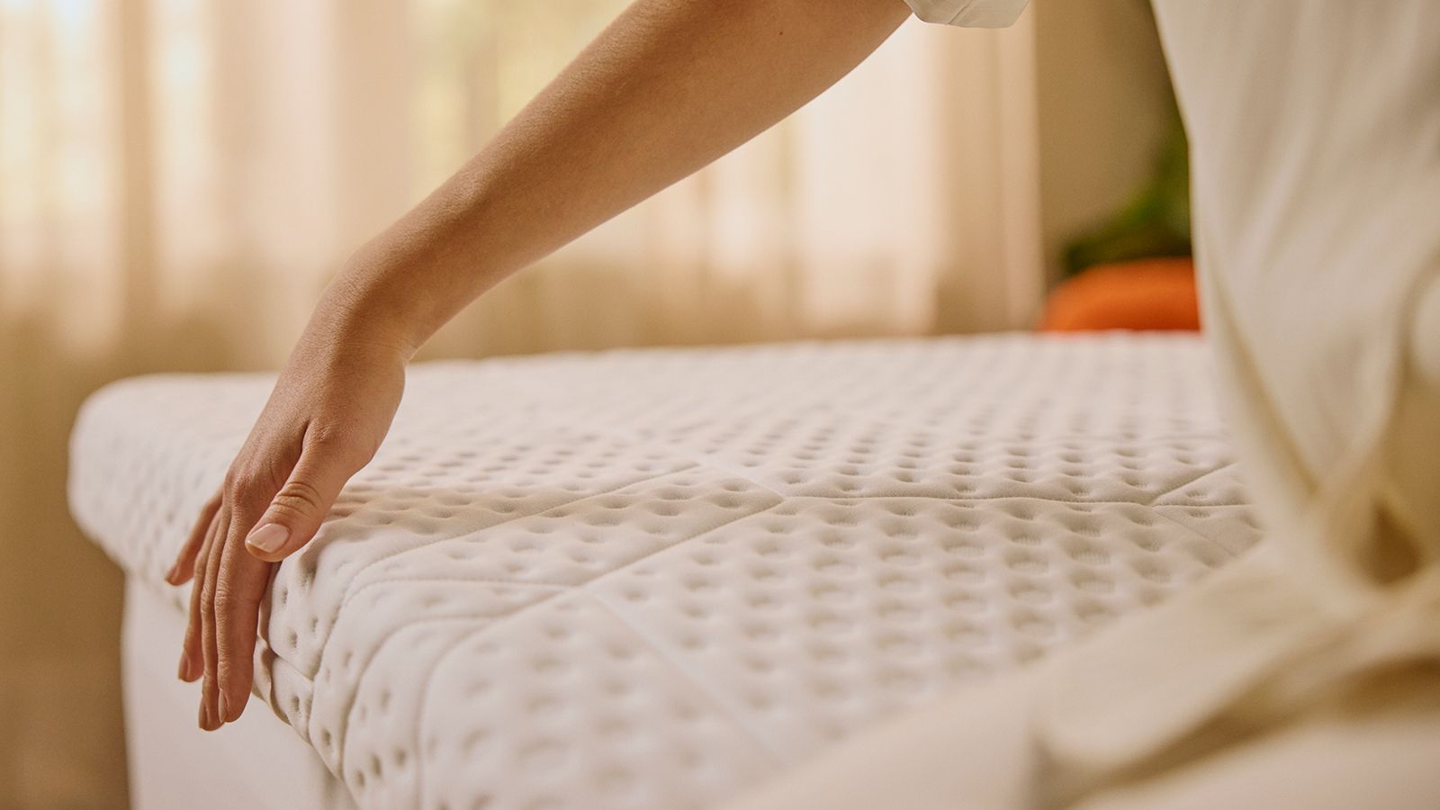 Hand die in de Emma-topper drukt en laat zien hoe zacht hij is en hoe goed hij drukpunten verlicht.