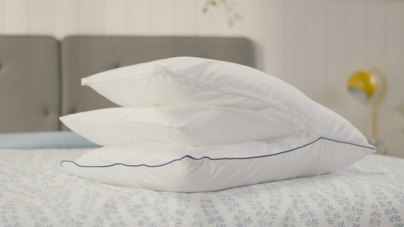 Emma Wolkenkussen op bed om alle verwijderbare lagen te zien. Op de achtergrond staat een grijs gestoffeerd hoofdbord en een gele lamp op een nachtkastje. Deze afbeelding toont het luchtige en stijlvolle ontwerp van het Emma Wolkenkussen in een huiselijke setting.