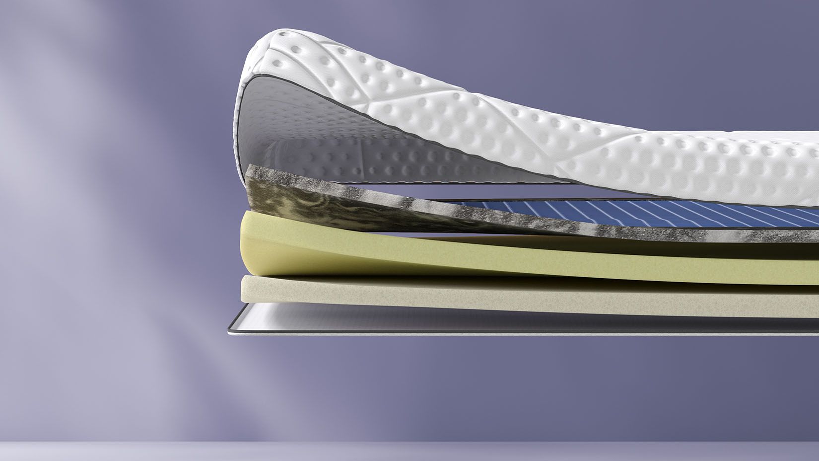 Coupe transversale d’un surmatelas montrant plusieurs couches, dont une couche supérieure texturée blanche et des couches intermédiaires bleues et jaunes. Le surmatelas porte l’inscription « Emma » sur le côté.