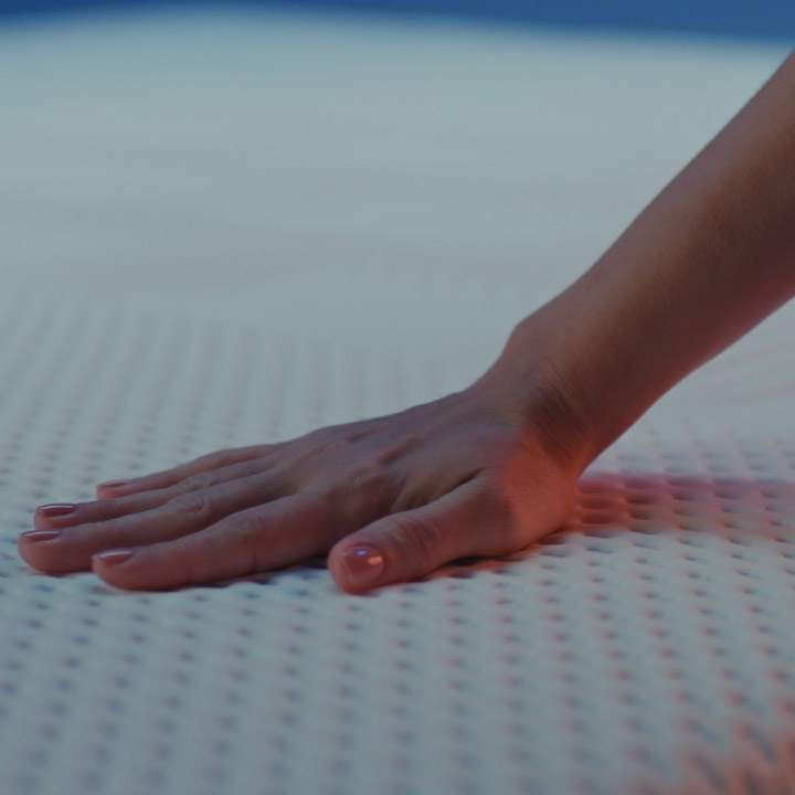 Close up of a woman's hand pressing on a textured mattress cover.