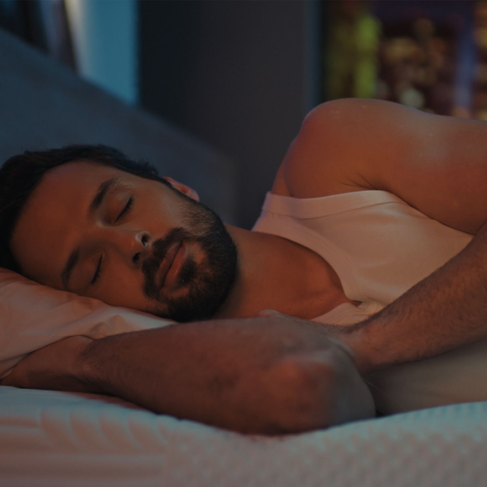 Man sleeping on Emma mattress in softly lit bedroom at night.