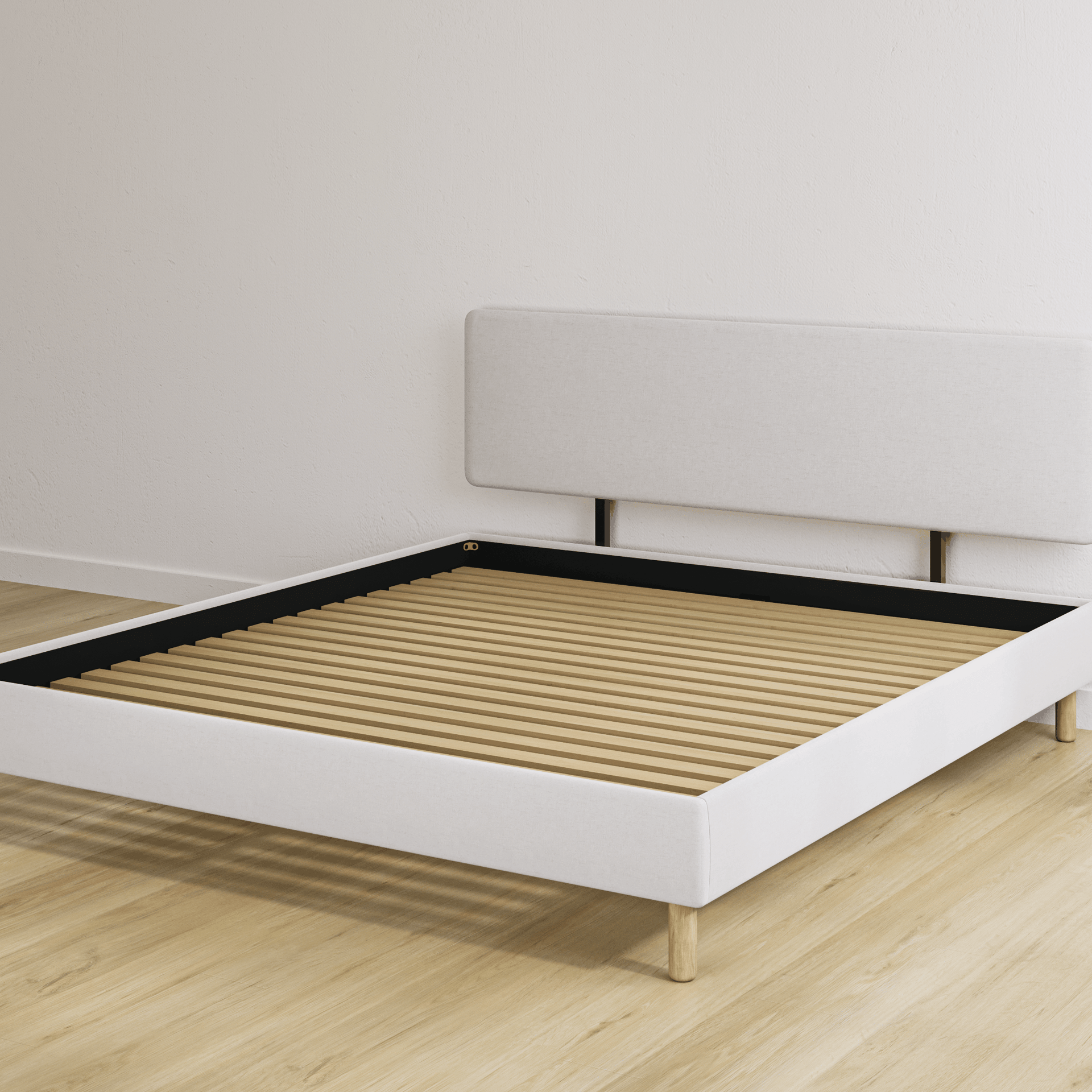 Beige bedframe met een hoofdeinde en een houten lattenbodem in een lege kamer met een lichte houten vloer.