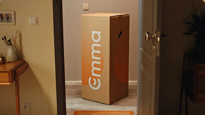 Boîte Emma avec matelas livrée à la porte d’entrée d’une maison, prête à être déballée.