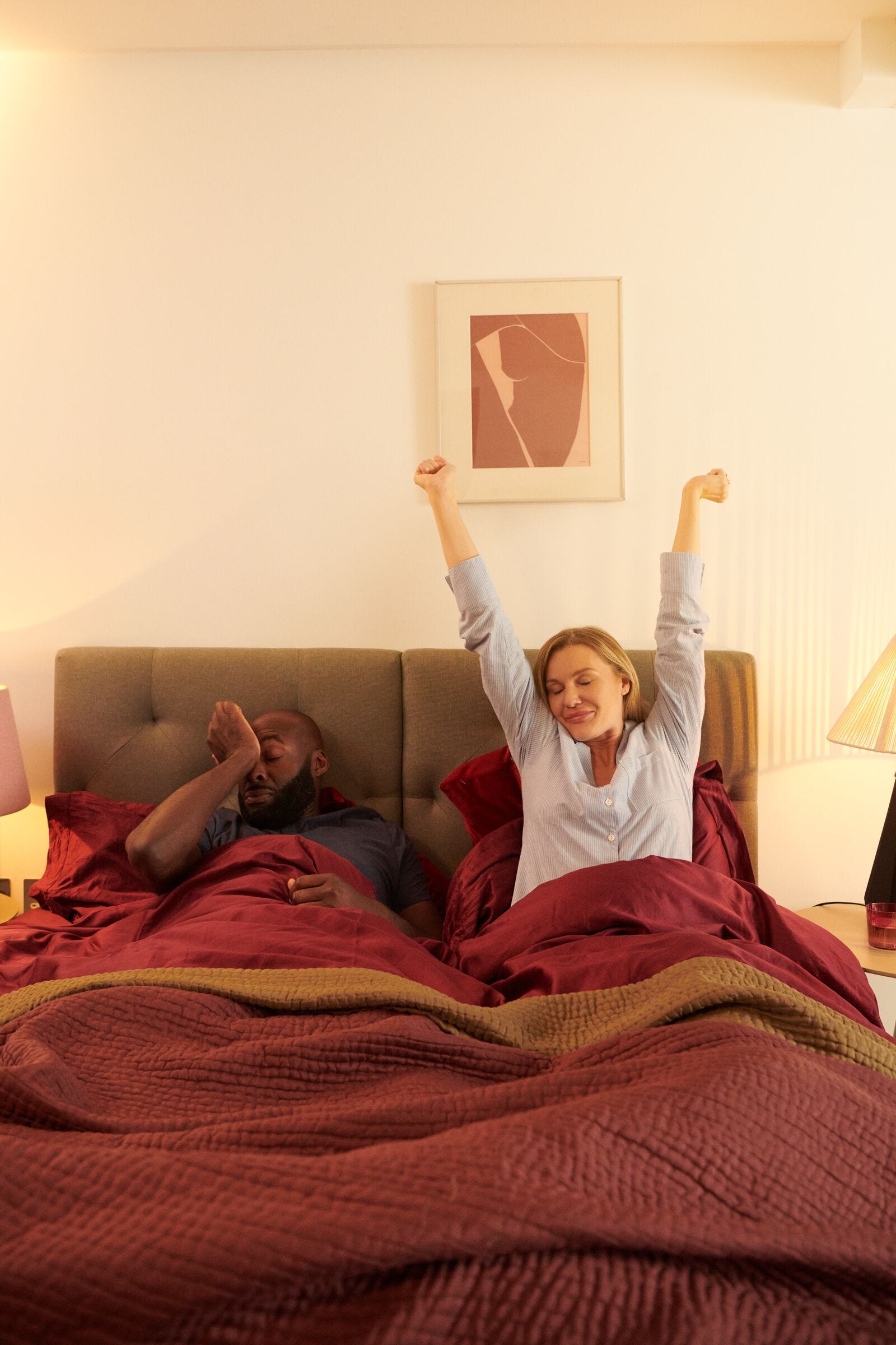 Un hombre y una mujer despertando juntos por la mañana en una cama gris