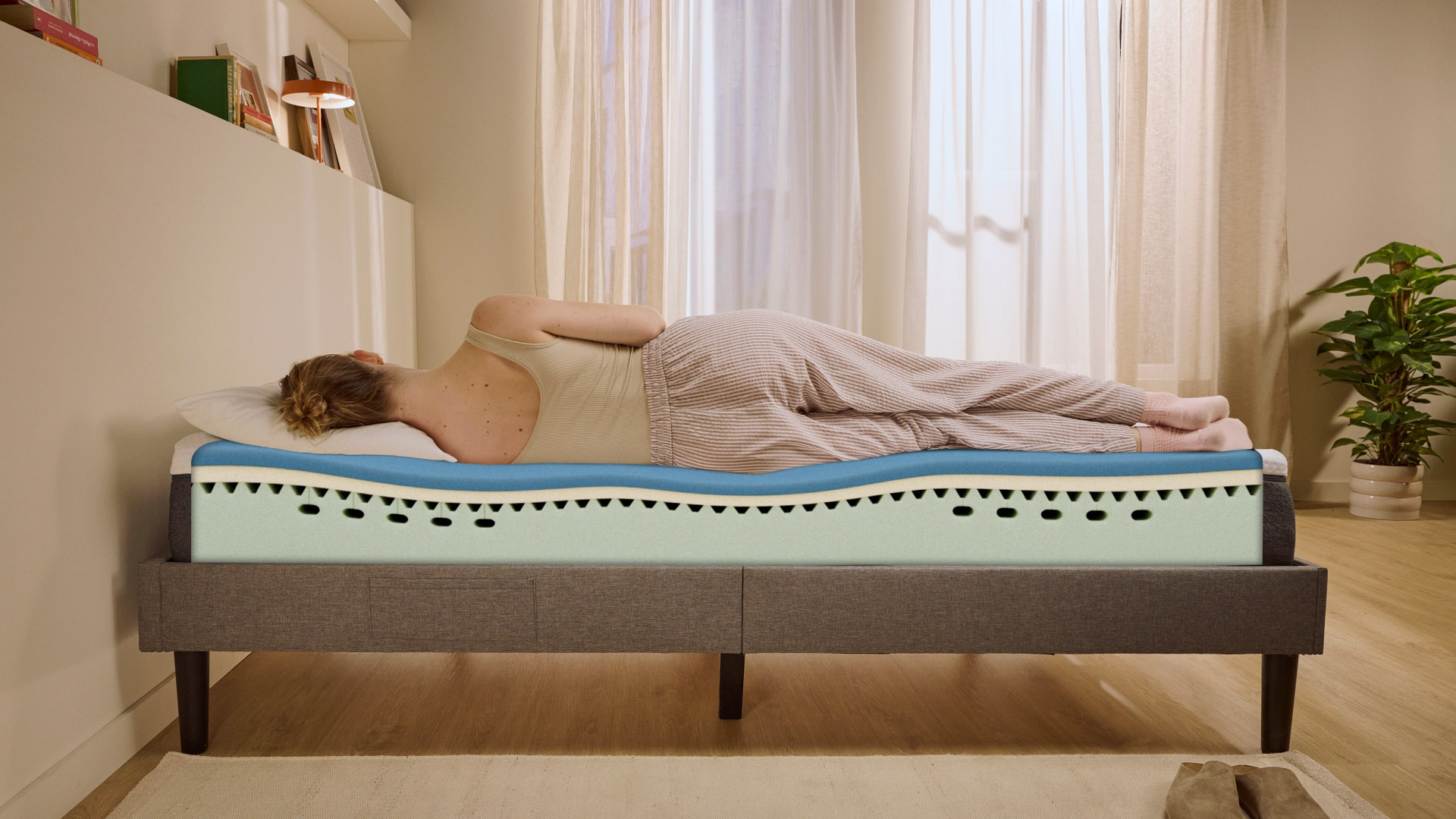 Person lying on their side on a white mattress in a relaxed sleeping position.