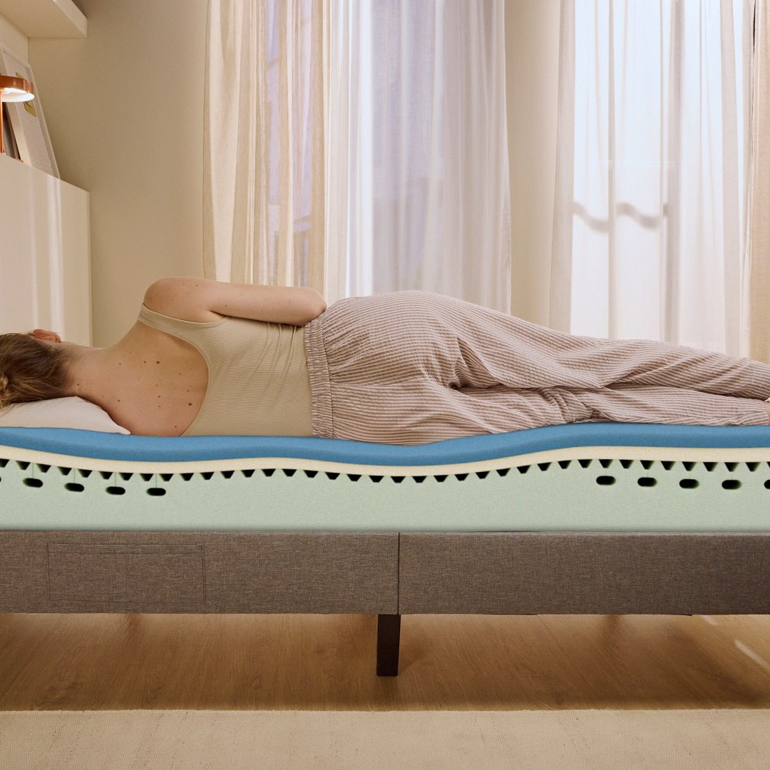 Person lying on their side on a white mattress in a relaxed sleeping position.