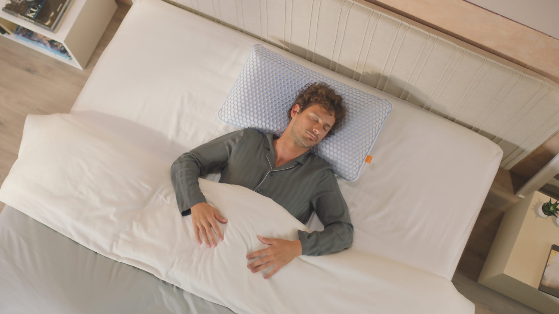 Hombre durmiendo en una cama blanca con la cabeza apoyada en la almohada viscoelástica Elite