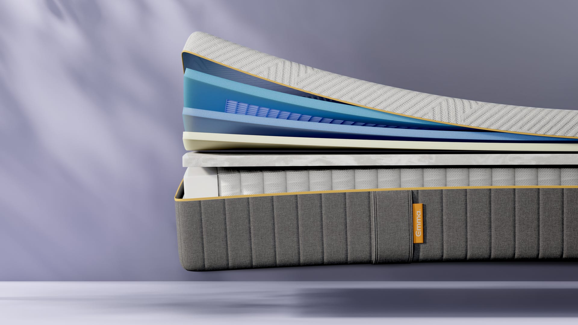 Dwarsdoorsnede van de Emma AirGrid® Matras met meerdere lagen schuim en een veerlaag, elk in verschillende kleuren en texturen. Onderaan een grijze stoflaag met het Emma-logo. Toont de opbouw en gebruikte materialen voor comfort en ondersteuning.