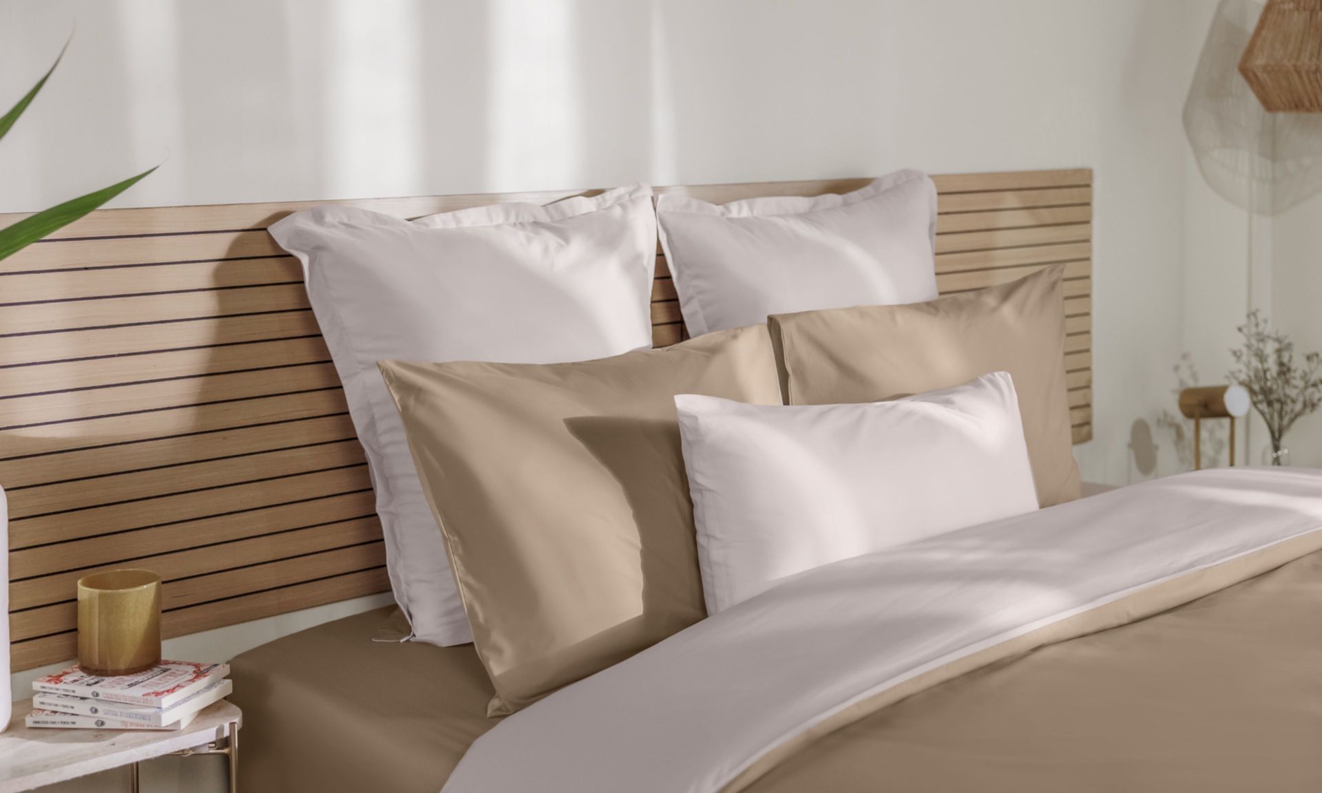 Letto con federe beige e bianche, copripiumino coordinato e testiera in legno a doghe.