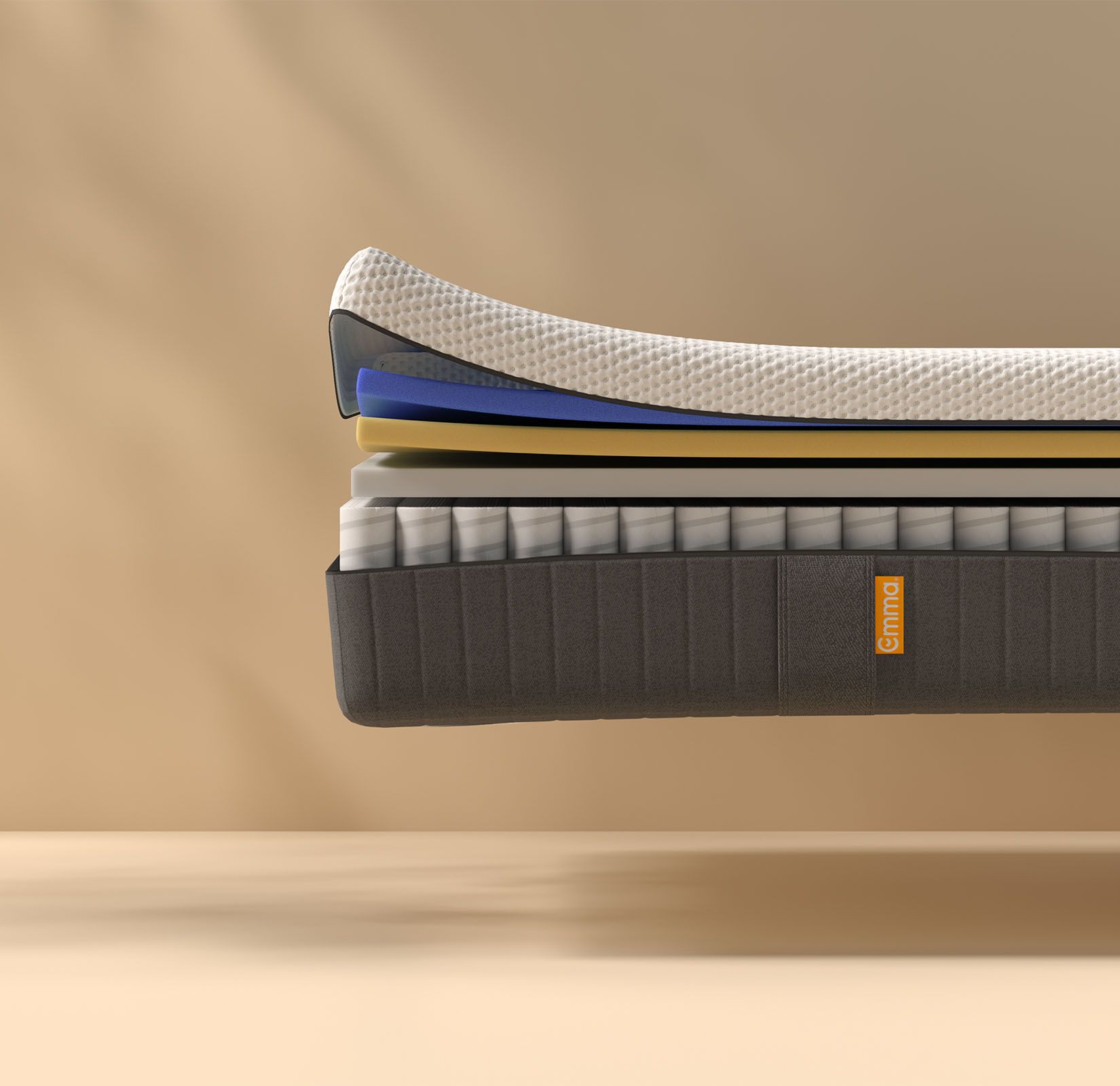 Coupe transversale d'un matelas montrant plusieurs couches, dont une couche supérieure texturée blanche, des couches intermédiaires bleues et jaunes, et un sommier dont les ressorts sont visibles. Le matelas porte l'inscription "Emma" sur le côté.