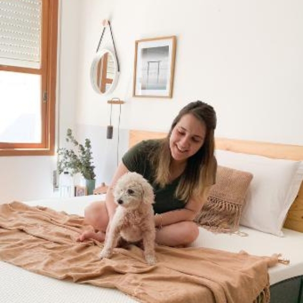 Mulher e seu cachorro numa cama com o colchão Emma Original
