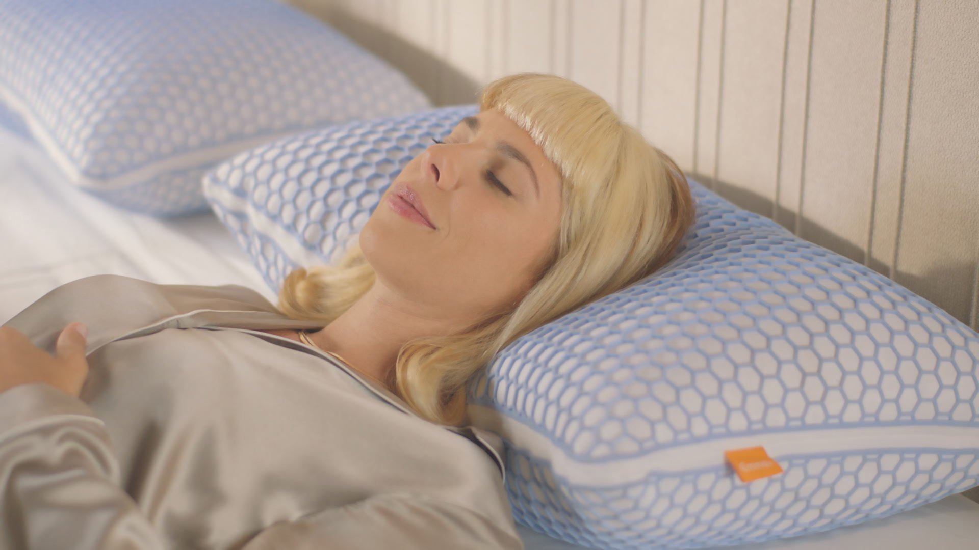 Persona sdraiata su un cuscino a motivo esagonale blu e bianco, con un secondo cuscino simile sullo sfondo.