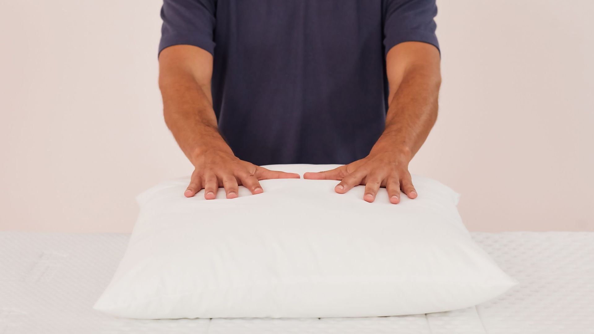 Persona presionando las manos en almohada microfibra blanca