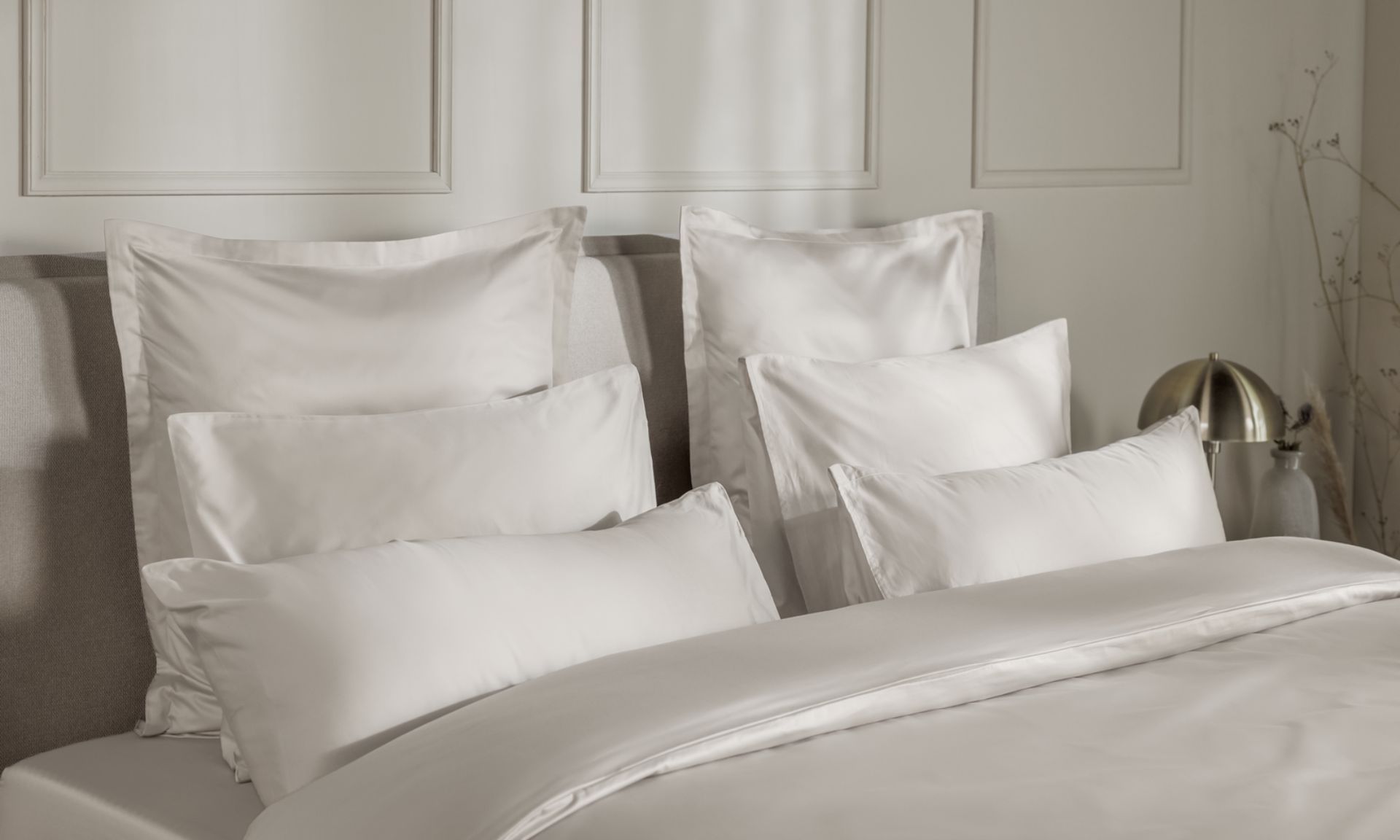 Letto ordinato con cuscini e piumone bianchi.