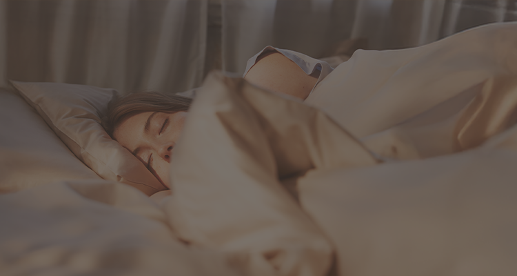 A person sleeping comfortably in soft beige bedding, with an Emma mattress and an orange heart graphic displayed beside them.