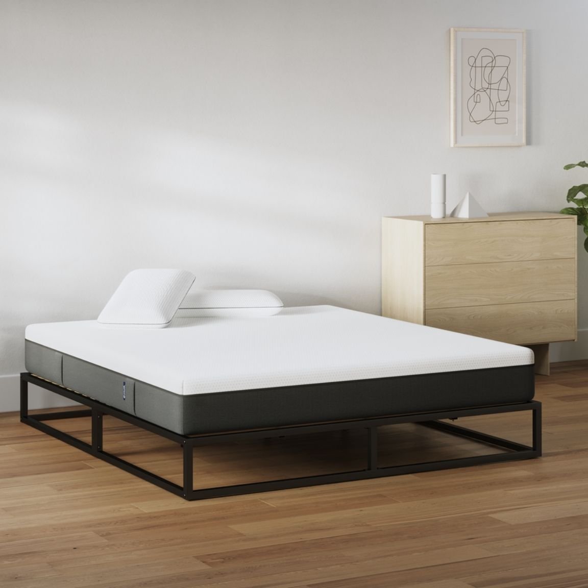 Camera da letto minimal con letto a struttura metallica nera, materasso bianco e due cuscini.