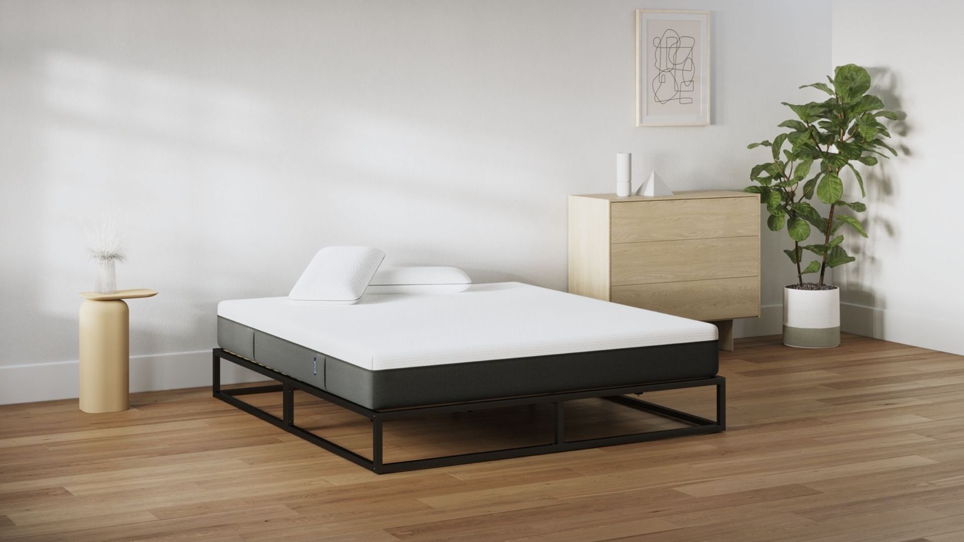 Camera da letto minimal con letto a struttura metallica nera, materasso bianco e due cuscini.