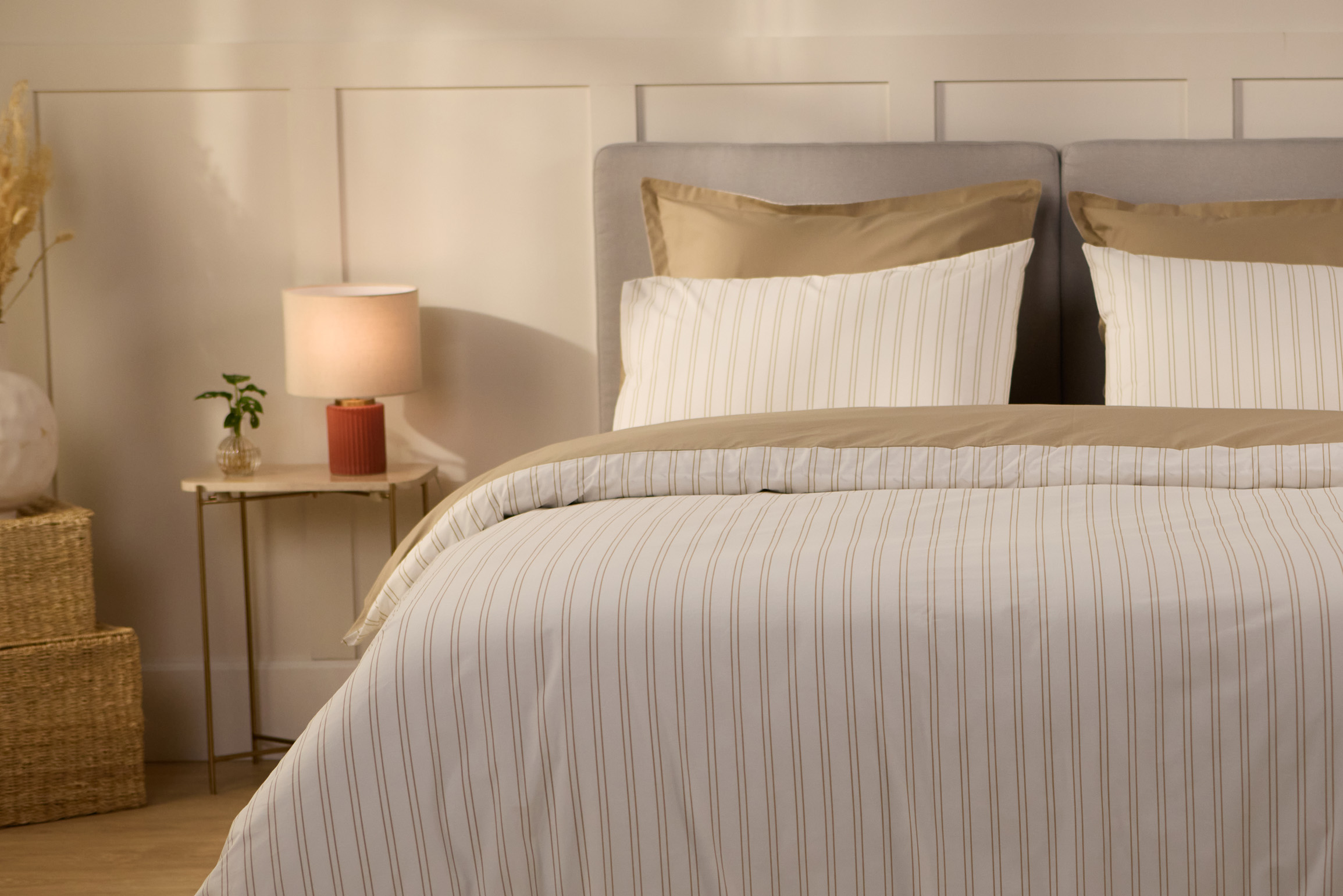 Bett mit Bettbezug mit beigen Streifen.