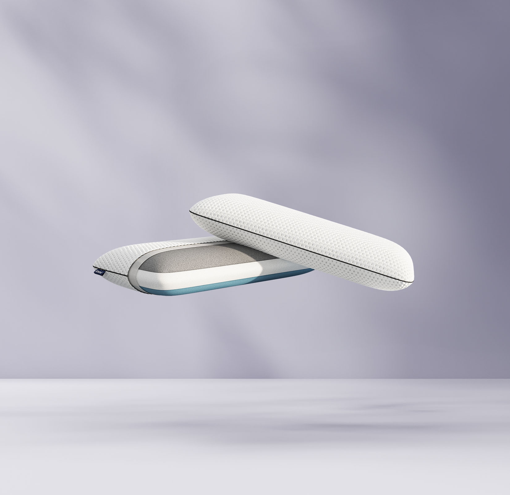 Deux oreillers blancs modernes en mousse à mémoire de forme avec des housses en filet flottant, l'un montré fermé, l'autre ouvert pour révéler les couches de mousse à l'intérieur, sur un fond violet clair et doux.