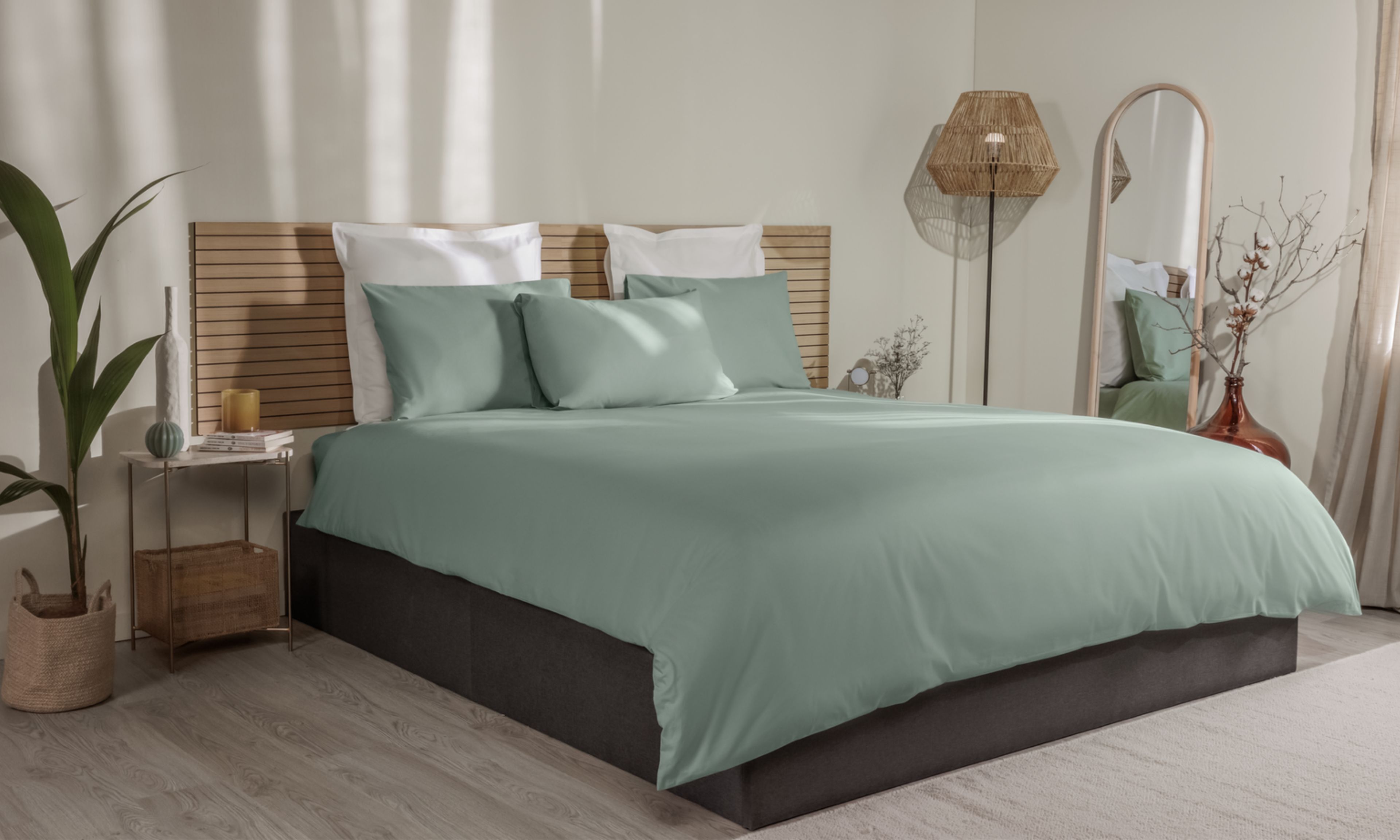 Letto con federe verde chiaro e bianche, copripiumino coordinato e testiera in legno a doghe.