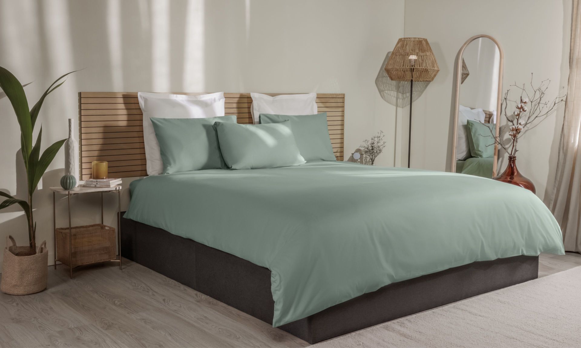 Letto con federe verde chiaro e bianche, copripiumino coordinato e testiera in legno a doghe.