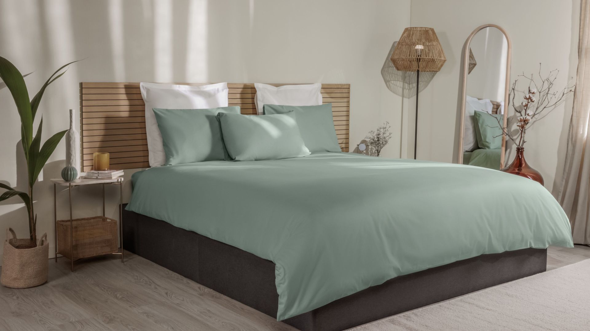 Letto con federe verde chiaro e bianche, copripiumino coordinato e testiera in legno a doghe.