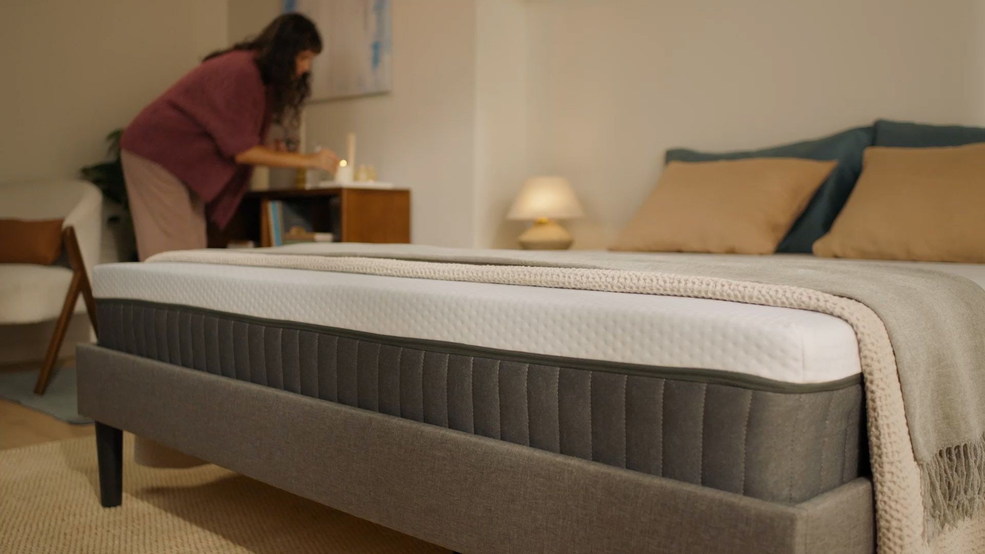 Personne assise sur un matelas hybride dans une chambre lumineuse, en train de s’étirer au réveil.