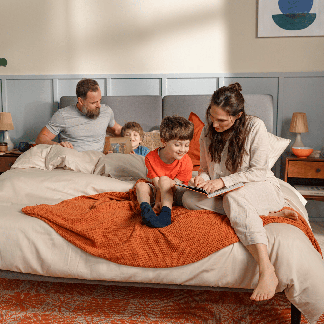 Familie liest gemeinsam auf dem Bett.