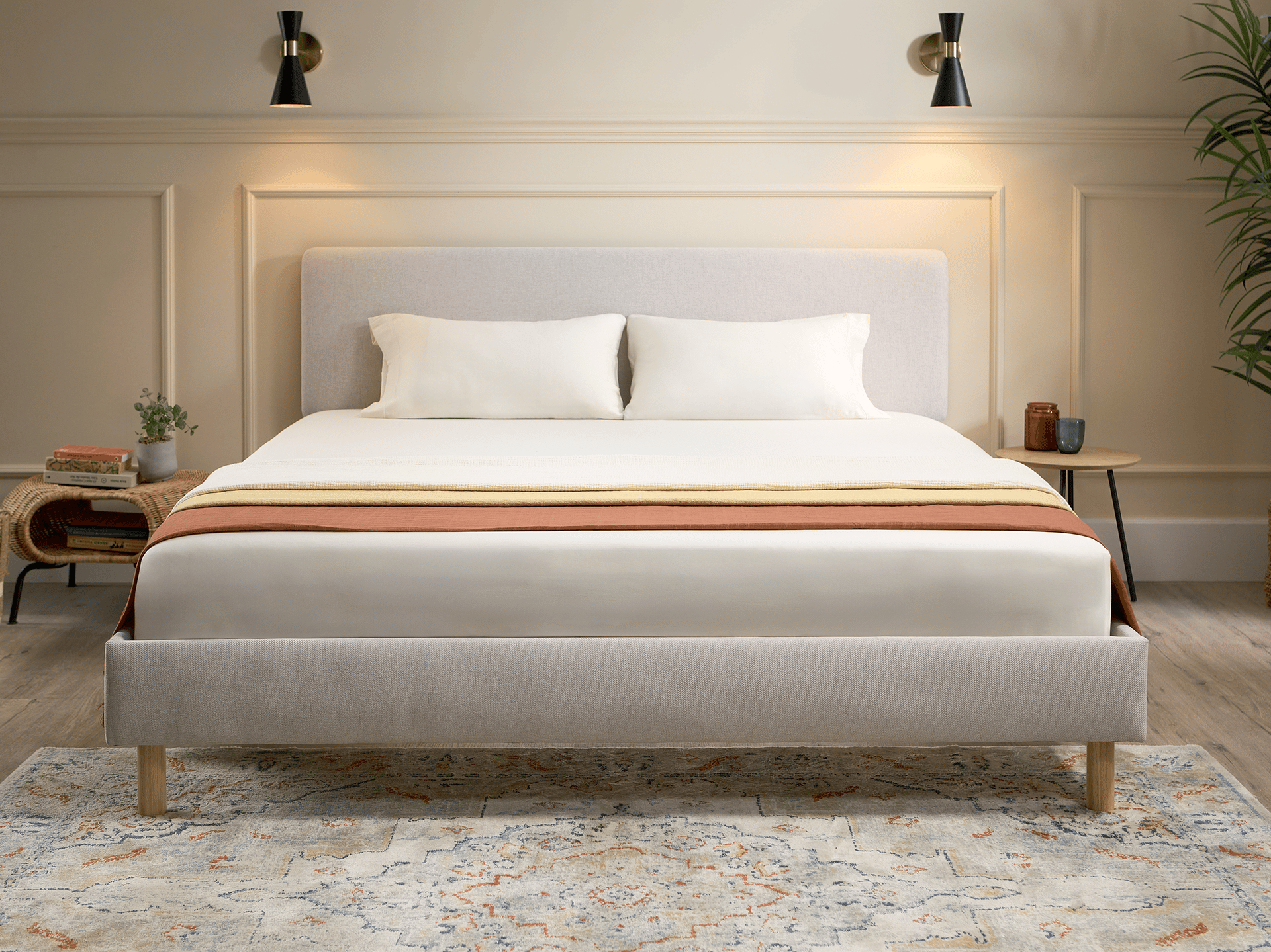 Emma Boxbed in beige with upholstered headboard and wooden legs, styled in a warm Scandinavian bedroom.