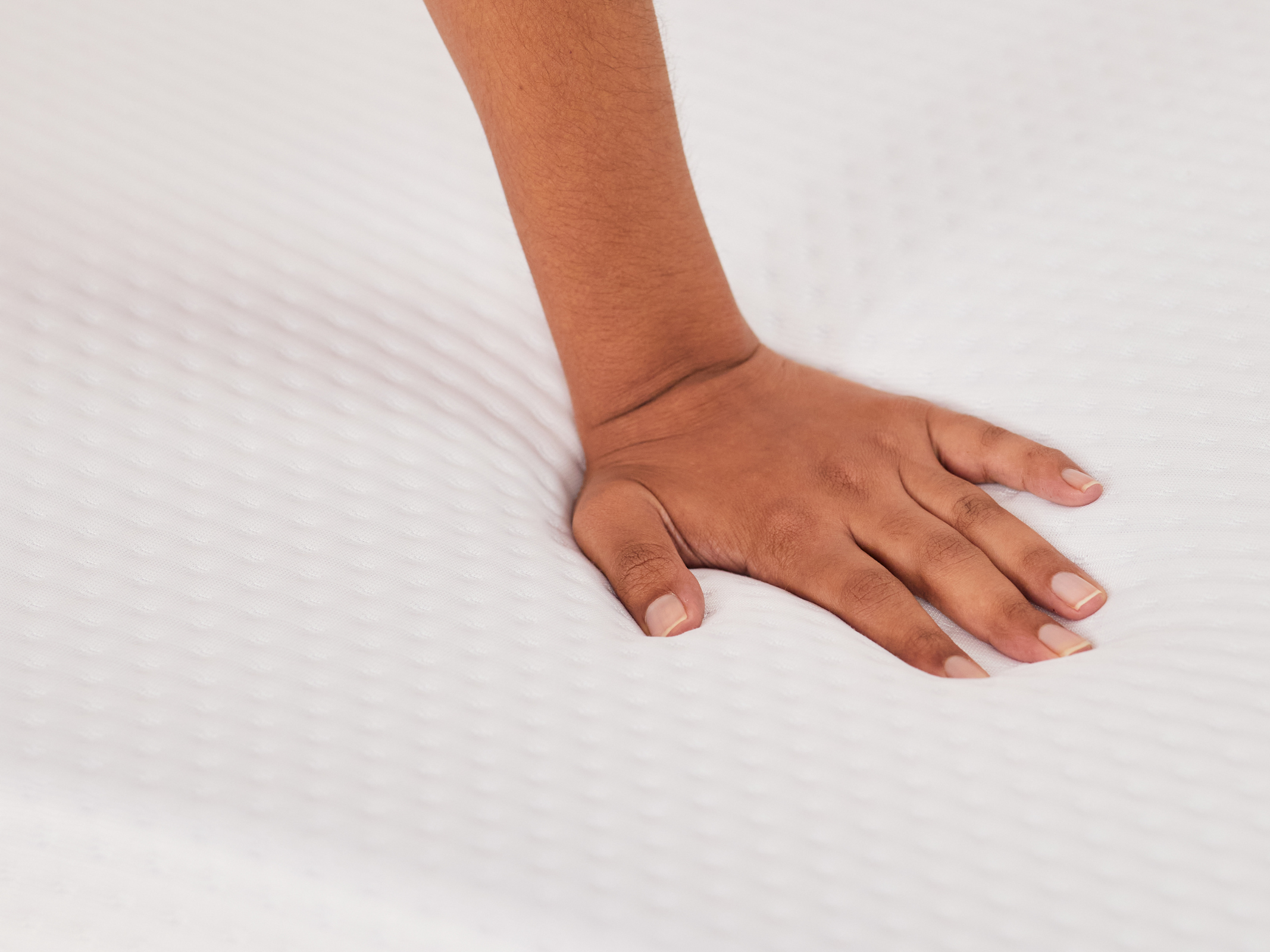 Hand pressing down on a topper.