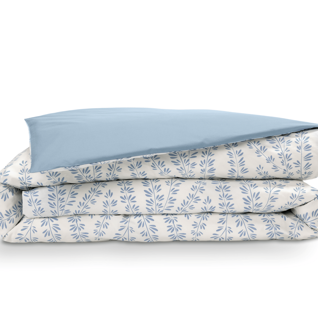 Copripiumino piegato con motivo floreale azzurro chiaro e bianco su sfondo bianco