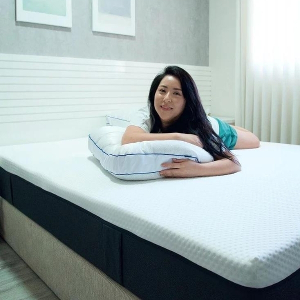 Moça deitada na cama sobre o travesseiro Antiestresse Emma. 