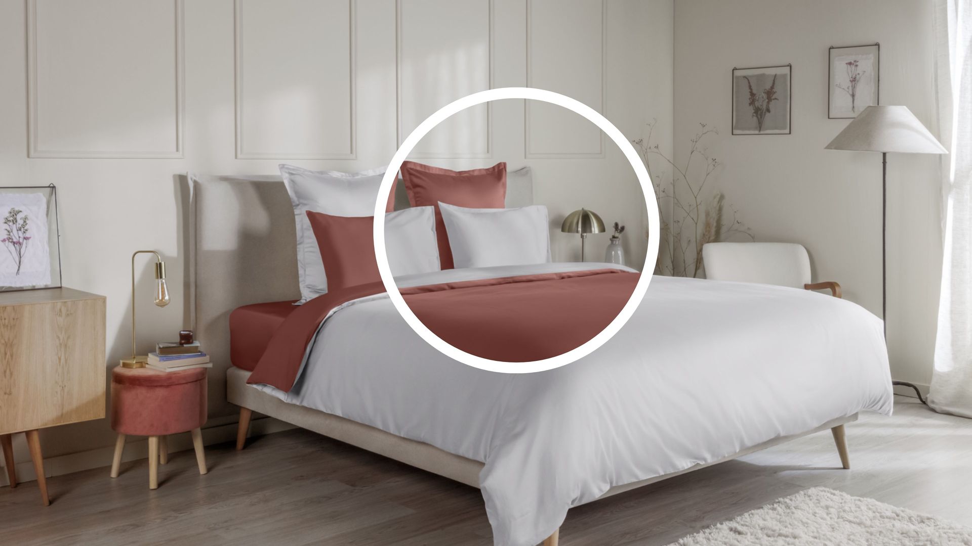 Letto ordinato con biancheria terracotta e bianca , in una camera decorata con mobili e quadri.