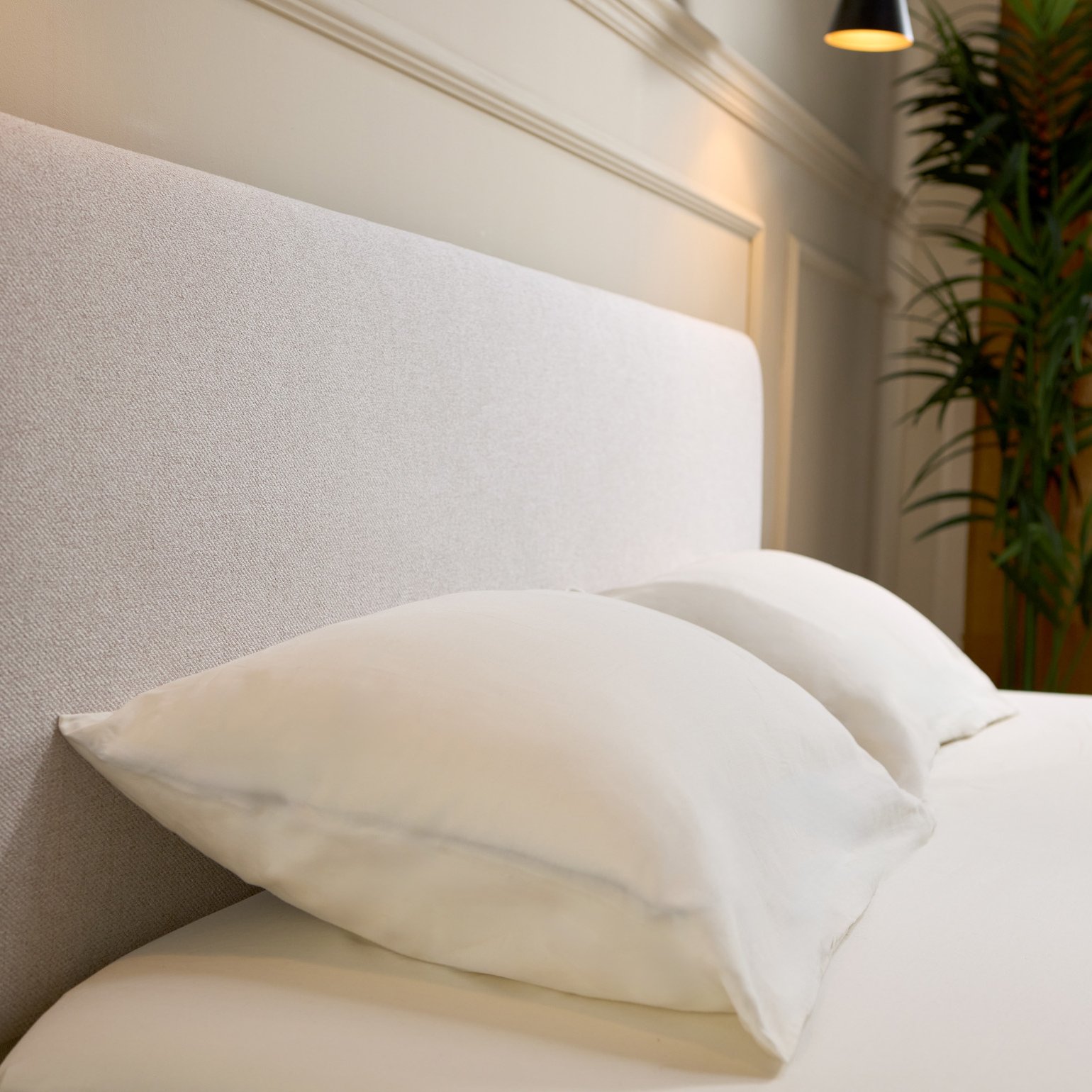 Close-up of Emma bed frame's light grey upholstered headboard with rounded corners, showing woven fabric texture.