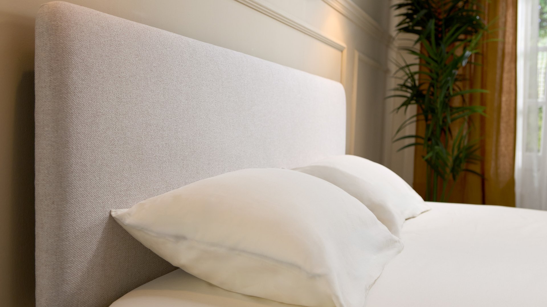 Close-up of Emma bed frame's light grey upholstered headboard with rounded corners, showing woven fabric texture.