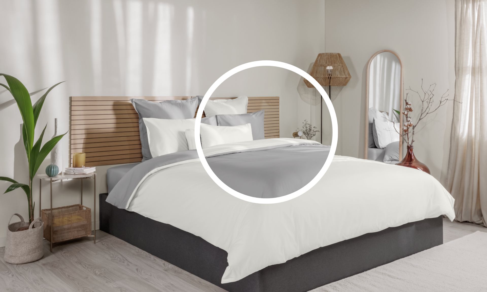 Letto ordinato con biancheria bianca e grigia, testiera in legno e decorazioni su entrambi i lati.