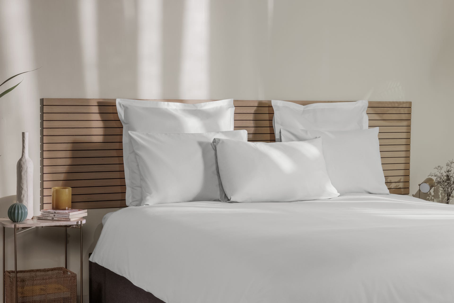 Uma imagem de almofadas numa cama composta, com fronhas de almofada Emma brancas