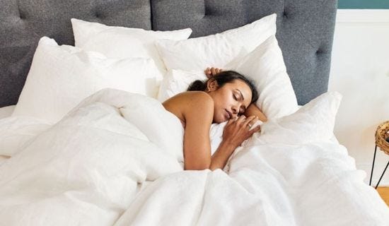Mujer durmiendo plácidamente usando la ropa de cama blanca de satén 100% algodón de Emma
