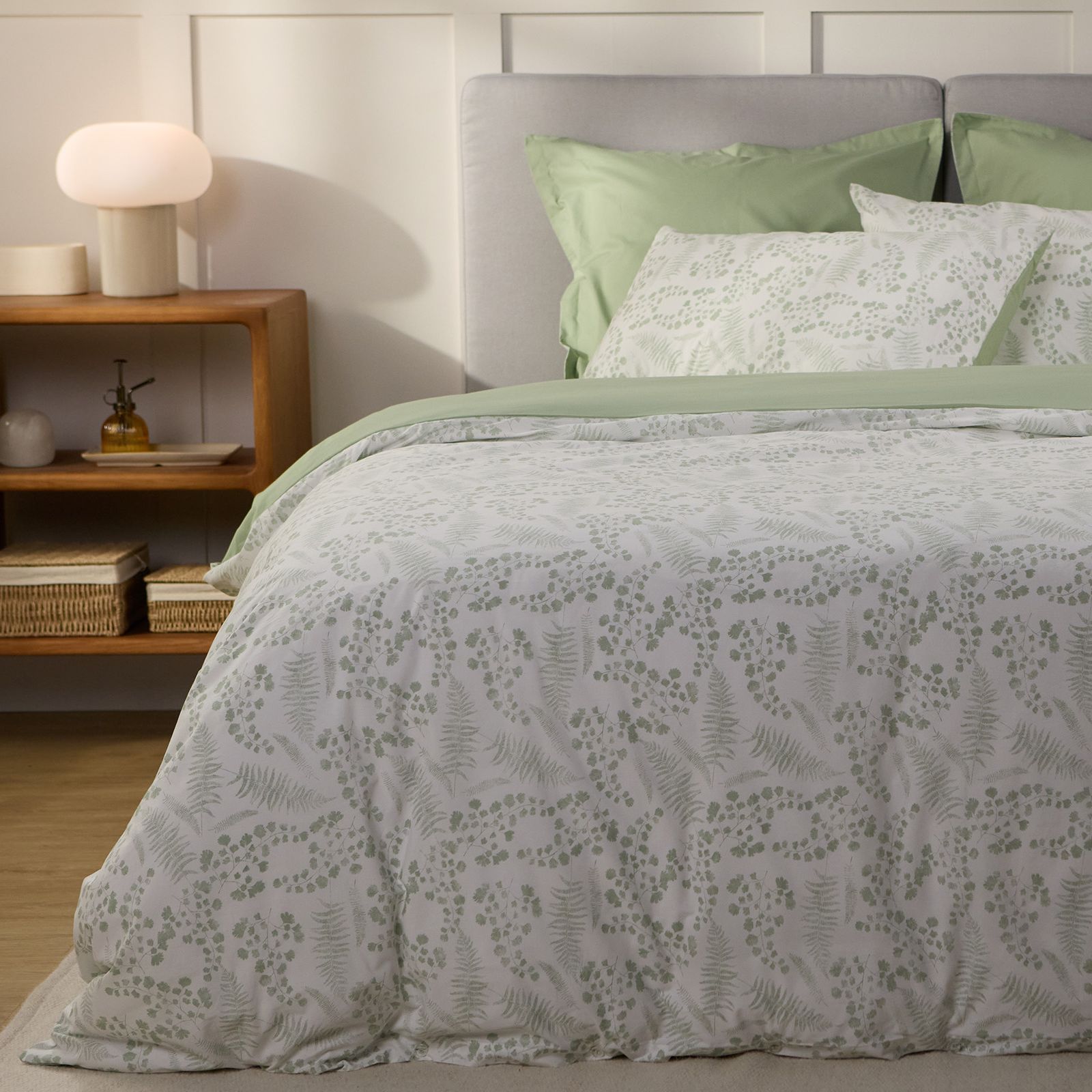 Bed styled with green botanical-print duvet cover and matching pillowcases.