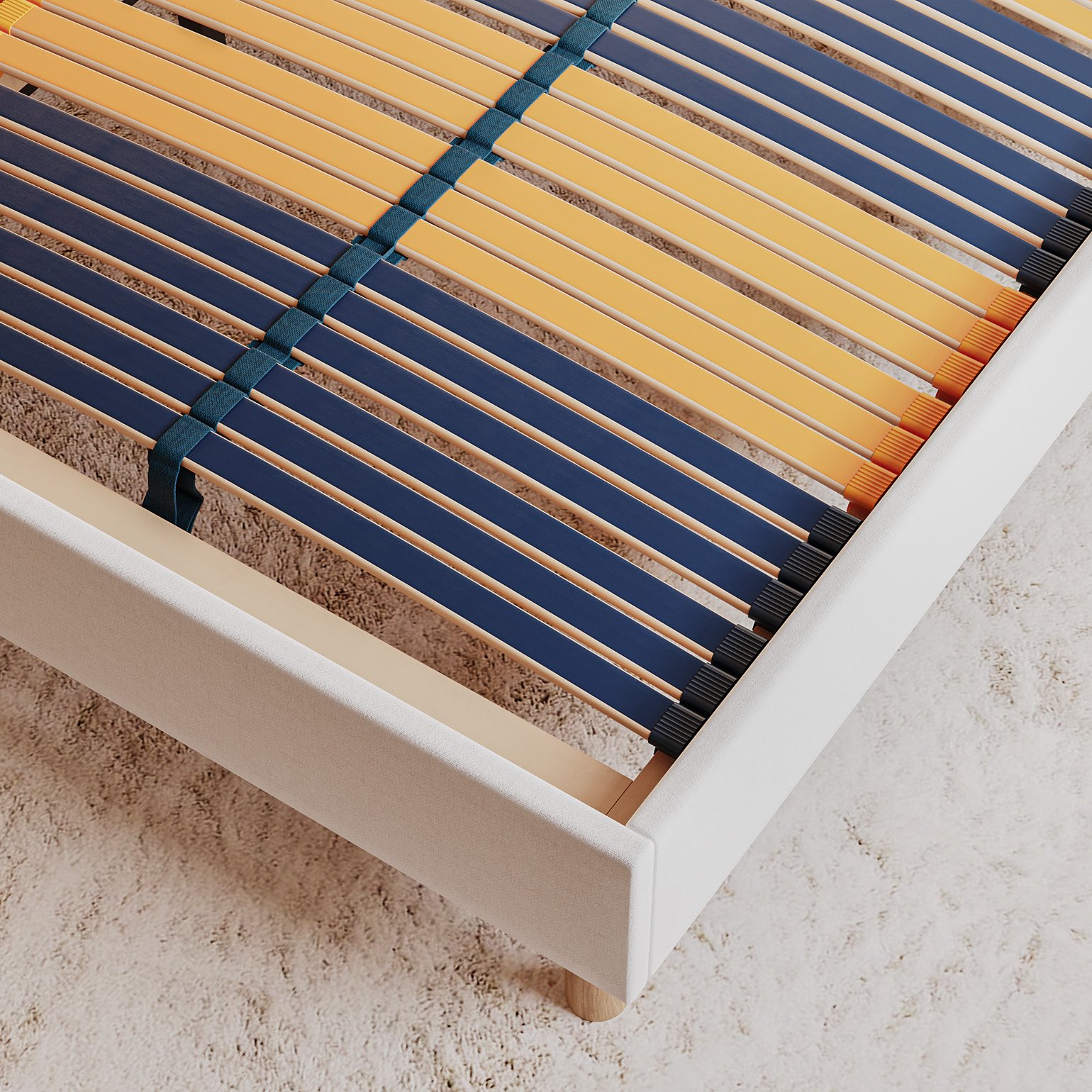 Gros plan du Emma Boxbed beige montrant le sommier à lattes flexibles avec des lattes bleues et jaunes.