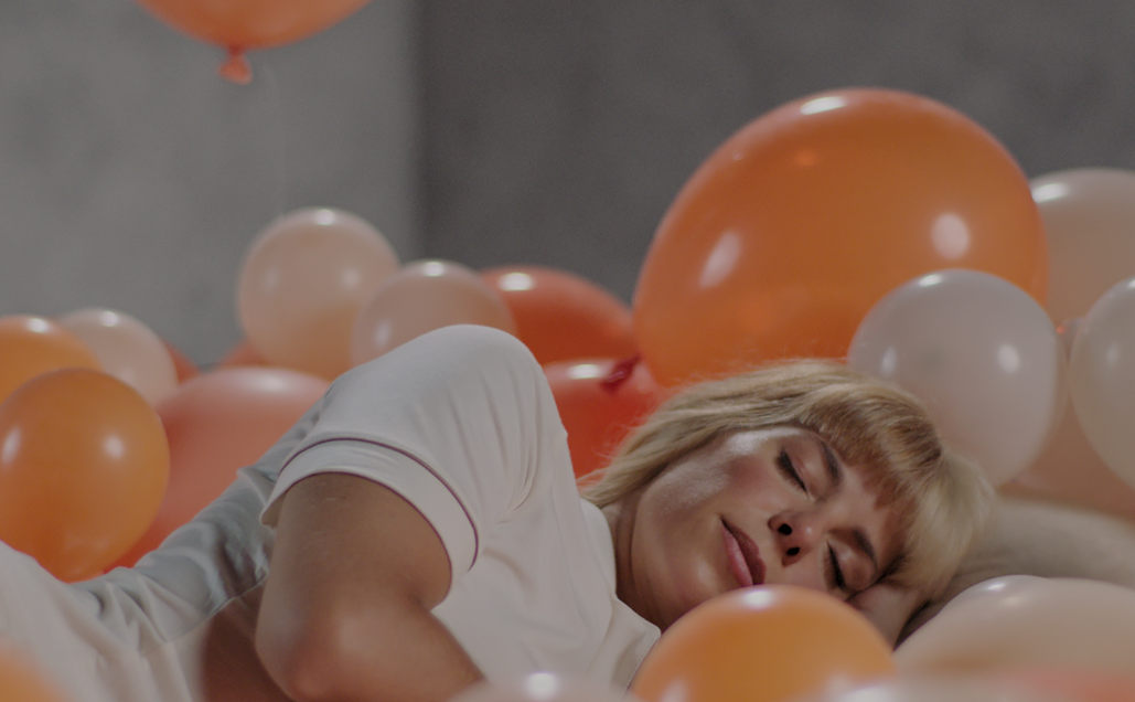 A girl sleeping on top of orange and white baloons.