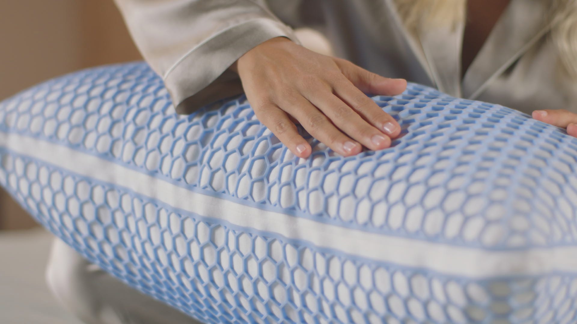 una chica pasa la mano por encima de la almohada de microfibra con tecnología de gel