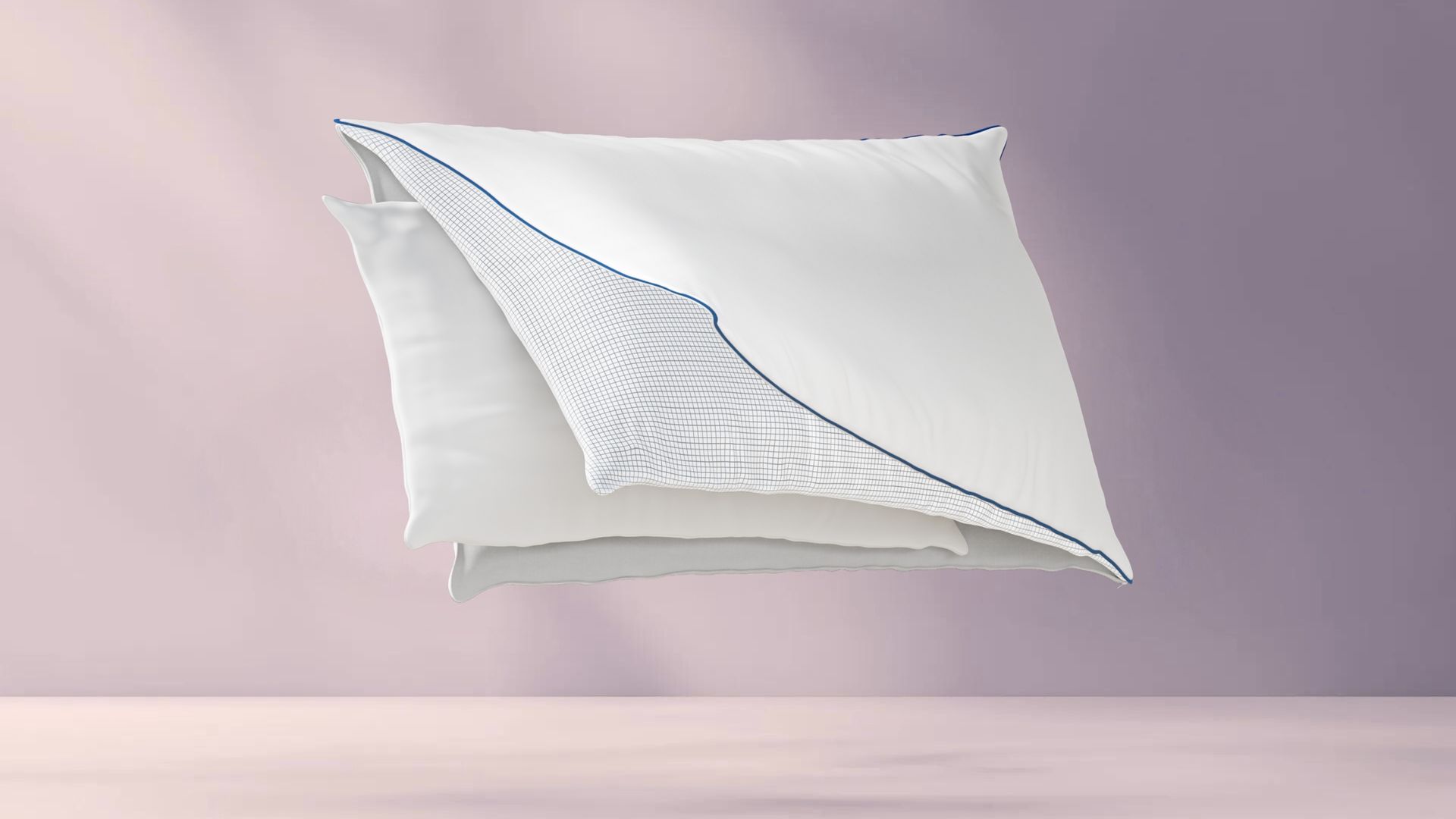 Drie lagen van het Emma Premium Wolkenkussen: witte buitenlaag met blauwe bies, middenlaag met rasterpatroon, en gladde witte binnenlaag; lagen zweven los van elkaar tegen pastelroze achtergrond.