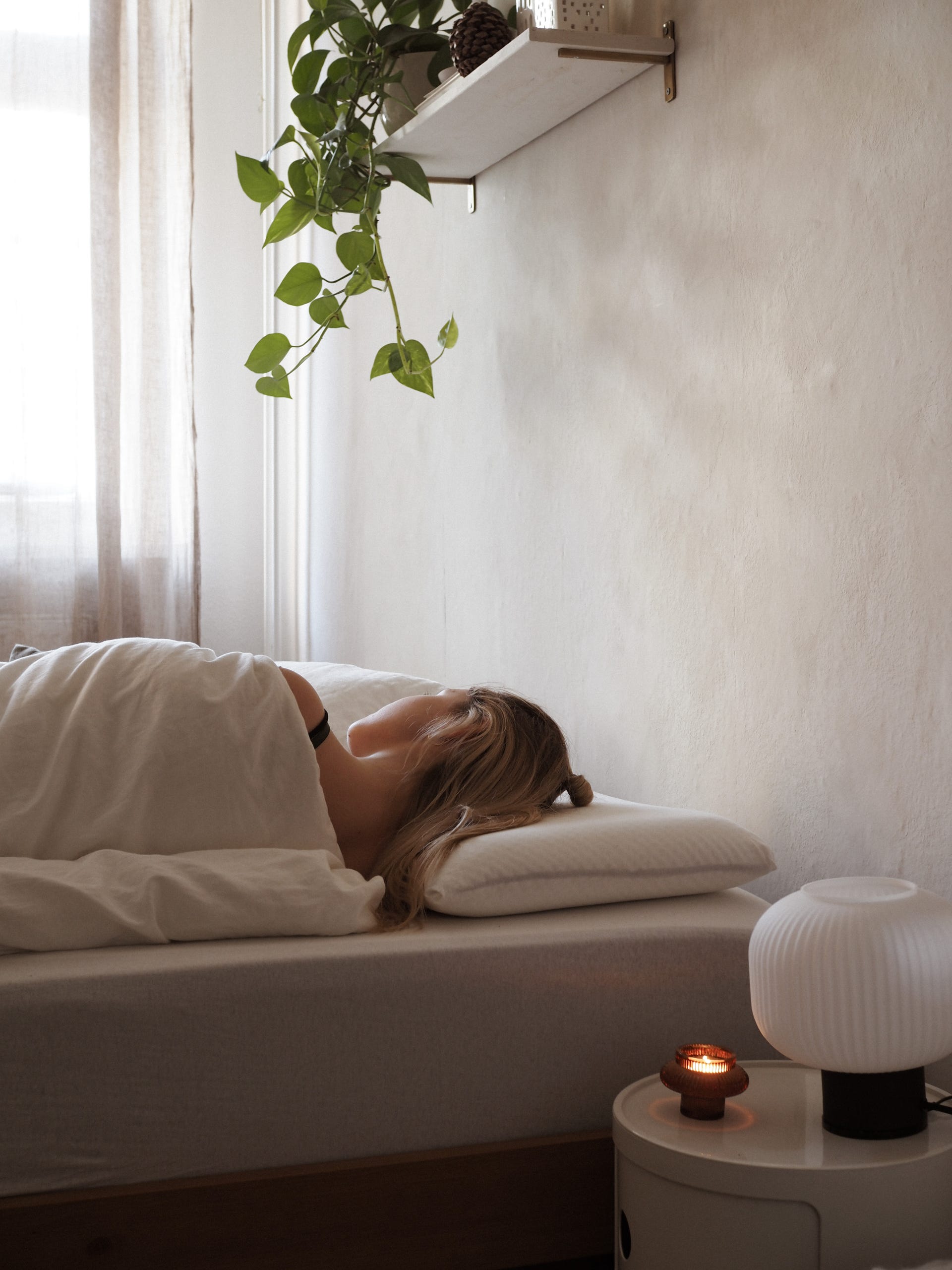 Frau schläft seitlich auf einem Emma Kissen in ruhigem, minimalistischem Schlafzimmer.