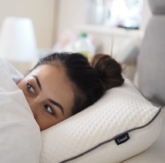 Woman lying on a white pillow labeled "Emma"