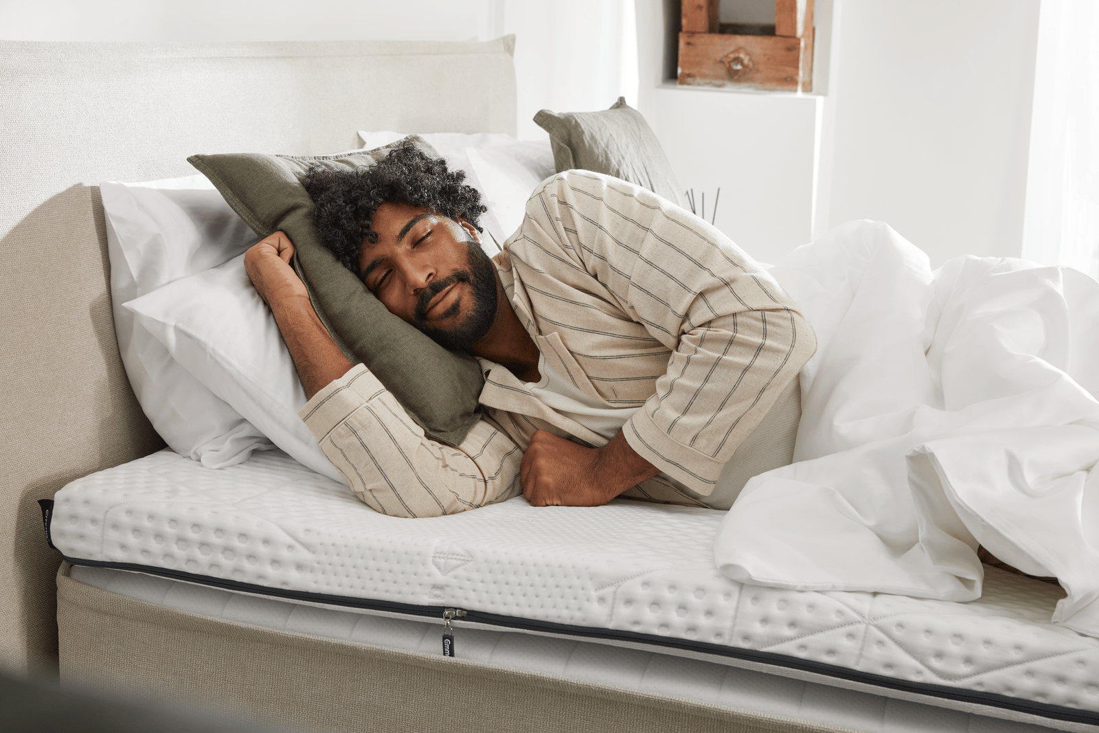 Chico moreno tumbado en lan cama sobre 3 almohadas