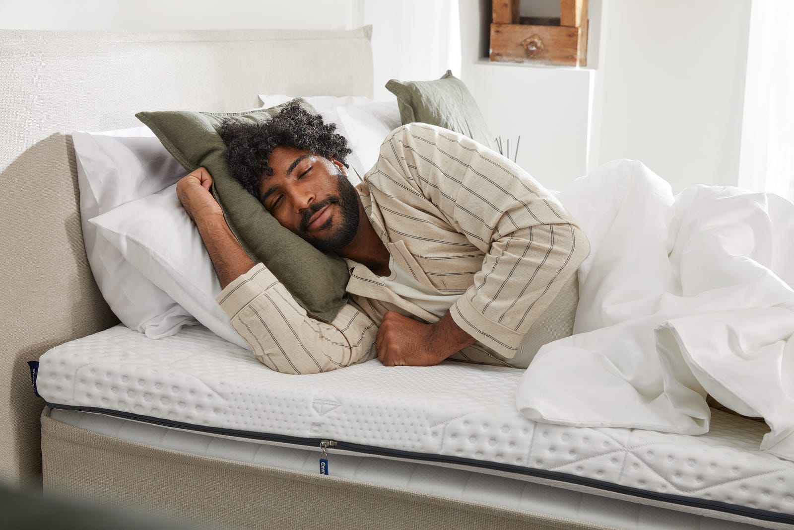 Chico moreno tumbado en lan cama sobre 3 almohadas